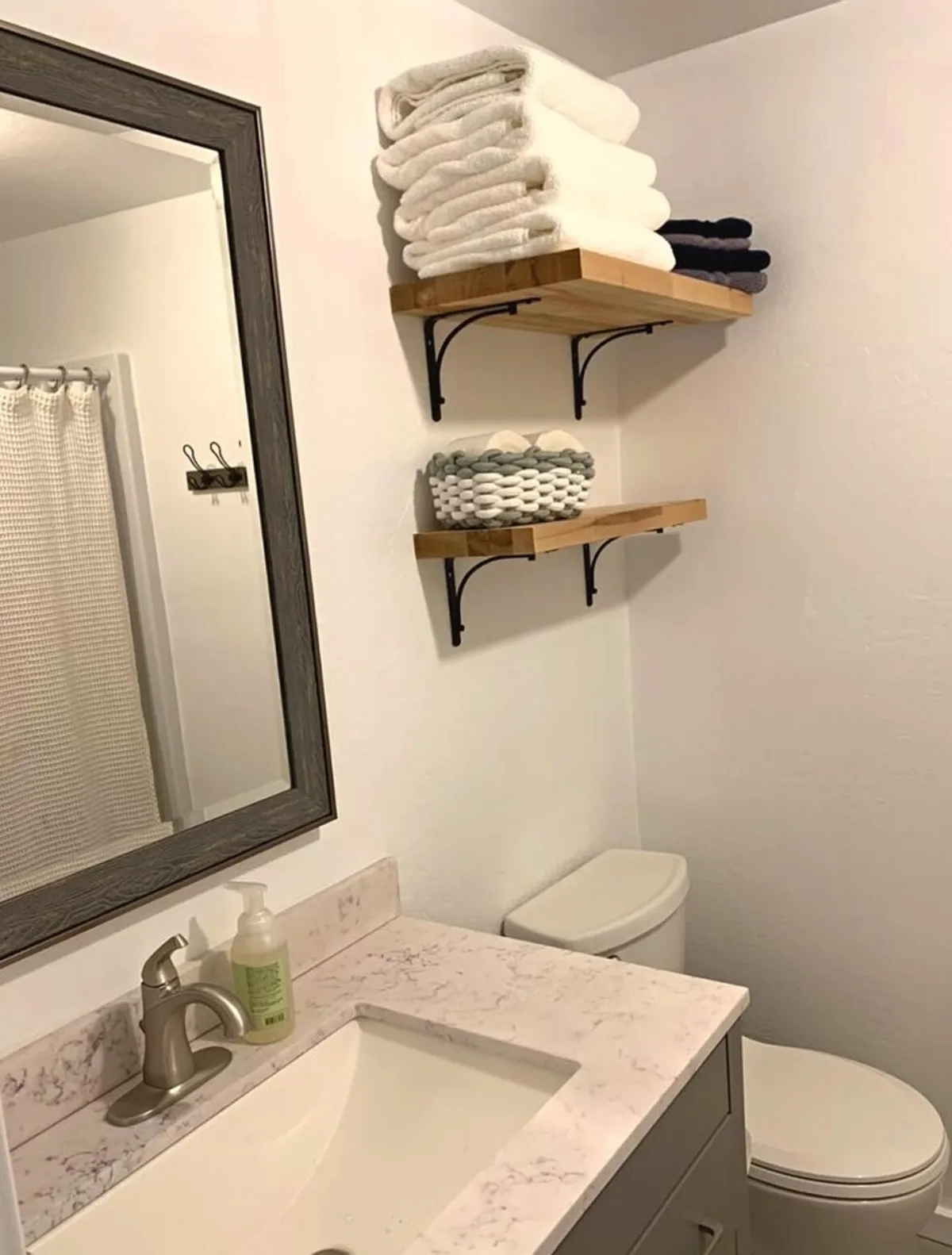 A calm, organized bathroom interior featuring a mirror above a modern sink, open shelves stacked with fluffy towels, and a tranquil palette. The overall setup evokes a sense of peacefulness and is ideal for winding down before bed or refreshing after a restful sleep.