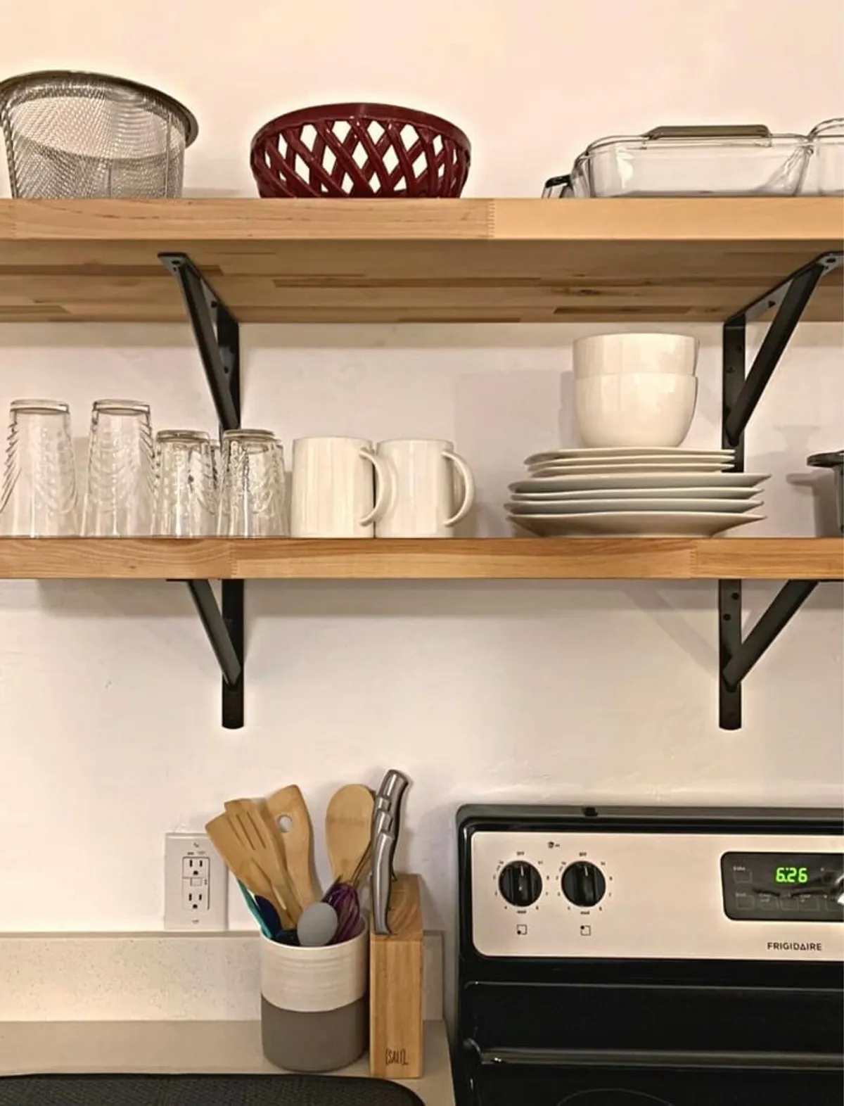 A close-up of open shelving adorned with a variety of kitchenware and glassware, including plates, bowls, and cooking utensils. The shelves are neatly organized, reflecting a well-stocked and thoughtfully designed kitchen.